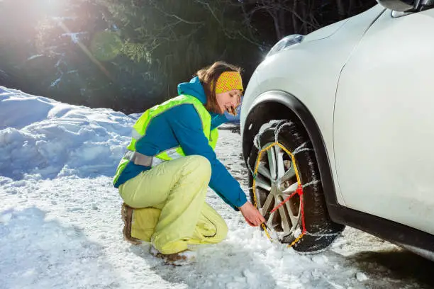 Photo of Woman put winter chains on car wheel for icy road