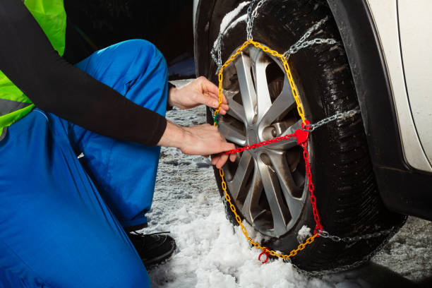 istock Man hands close-up putting chains on the car wheel 1412972699