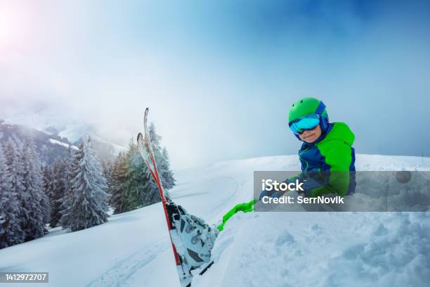 Side View Of The Boy With Mountain Ski Sit In Snow Stock Photo - Download Image Now - 10-11 Years, Activity, Beauty