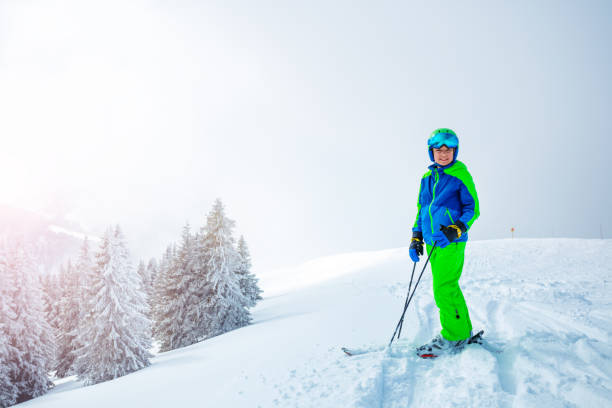 istock Boy with alpine mountain ski stand over snowy forest on back 1412972715
