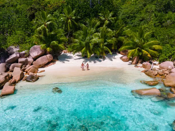 Photo of Anse Source d'Argent, La Digue Seychelles, young couple men and woman on a tropical beach during a luxury vacation in the Seychelles. Tropical beach Anse Source d'Argent, La Digue Seychelles