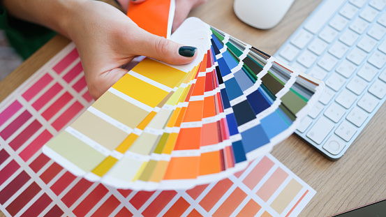 Top view of interior designer holding fan of colourful samples in hand. Woman searching proper colour for promotion. Design and art concept
