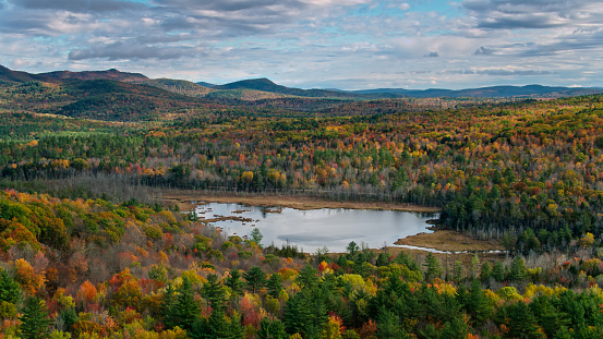 Aerial shot of autumn colors in New England near Sumner, Maine on a partly cloudy day.