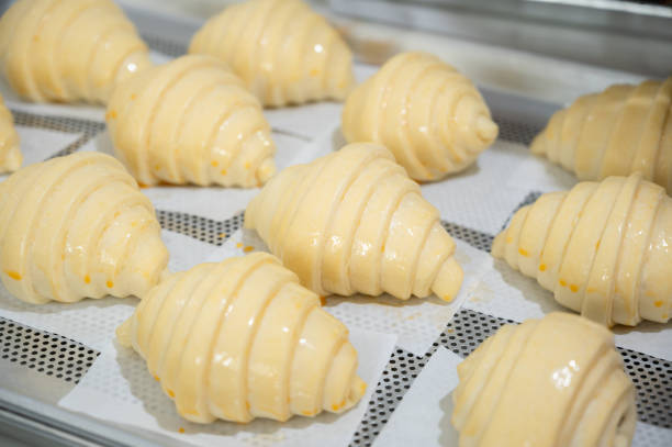 Baking classic croissants at home and brushing egg on uncooked croissants.
