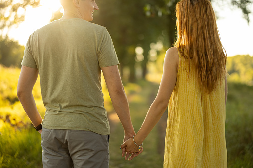 Young couple standing next to each other in nature and holding hands.