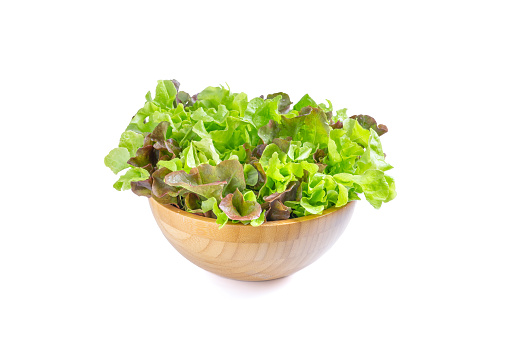 Red and Green oak lettuce In a wooden bowl on a white background.