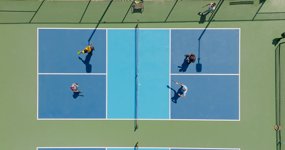 Top down drone shot of a group of people playing a doubles game of pickleball.