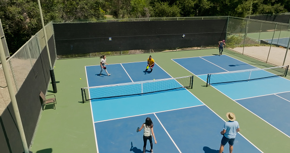 Drone shot of a mixed doubles game of pickleball. Another game is going on in the next court.