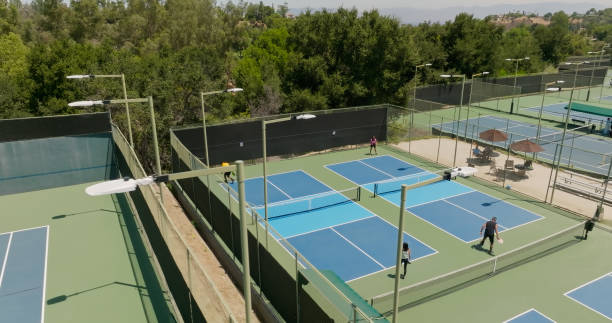 Drone shot of a complex of pickleball courts where two games are going on.