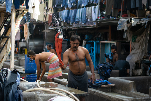 Mumbai, India - 14 February 2022, Man washing clothes in world famous dhobi ghat. Indian Labour, worker, labor, poor, hard working. Skill India. Jobs, migrant, poverty, wages, clothes, wash, clean.