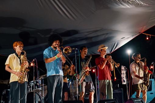 Music group playing a live concert at an outdoor music festival at night in Japan
