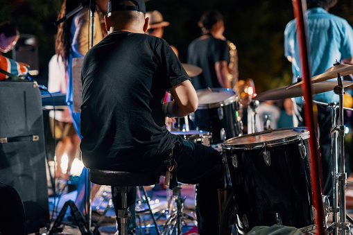 Rear view of a music group playing a live concert at an outdoor music festival at night in Japan