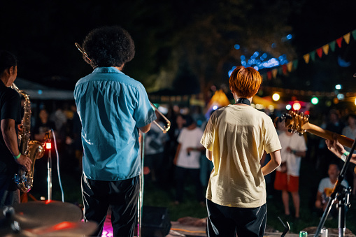 Rear view of a music group playing a live concert at an outdoor music festival at night in Japan