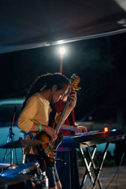 uomo adulto medio che suona un basso in una band in un festival di musica all'aperto - band name immagine foto e immagini stock