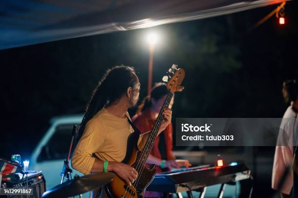 Mid Adult Man Playing A Bass Guitar In A Band At An Outdoor Music Festival Stock Photo - Download Image Now