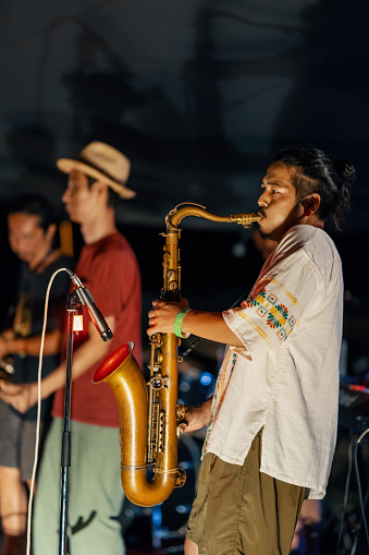 Man playing saxophone at an outdoor music festival in summer at night