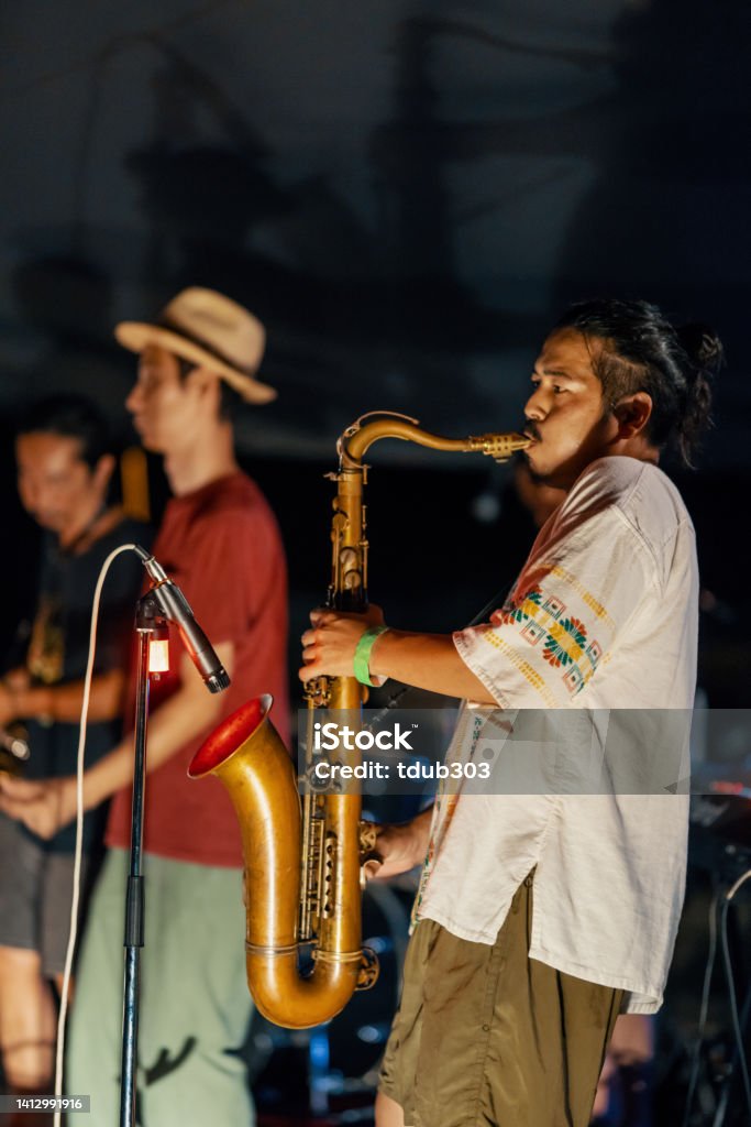 Man playing saxophone at an outdoor music festival Man playing saxophone at an outdoor music festival in summer at night 30-34 Years Stock Photo
