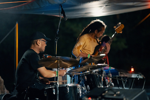 Mid adult man playing the drums at an outdoor music festival in Japan at night
