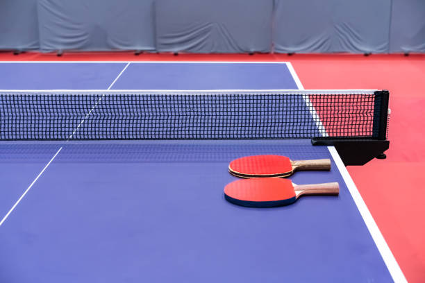 istock Two pingpong table tennis rackets for playing are laid on next to net on the blue table. This is one of ping pong sports equipment for players. 1412996697