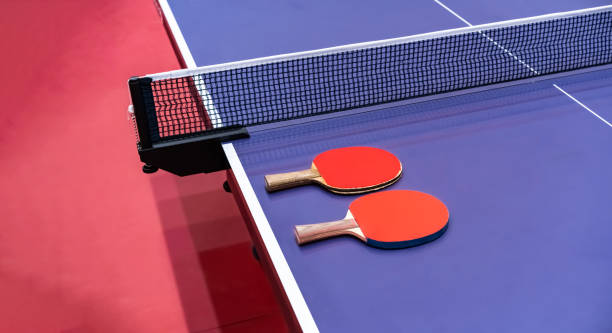 istock Two pingpong table tennis rackets for playing are laid on next to net on the blue table. This is one of ping pong sports equipment for players. 1412996701