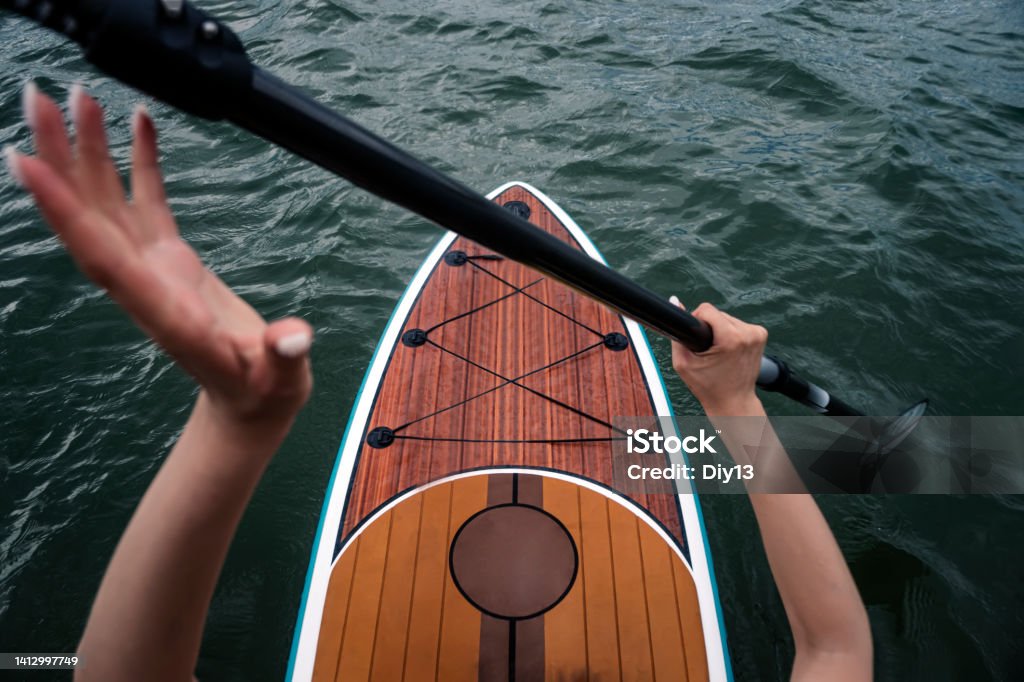 Sports girl on board for glanders surfing. A young slender woman floats on a board with a paddle. Surfing. Summer fun on the water. Healthy lifestyle. SUP on calm water. top view Sports girl on a board for glanders surfing. A young slender woman floats on a board with a paddle. Surfing. Summer fun on the water. Healthy lifestyle. SUP on calm water. top view Standup Paddleboarding Stock Photo