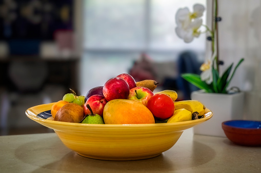 Yellow ceramic fruit bowl filled with a variety of fruit