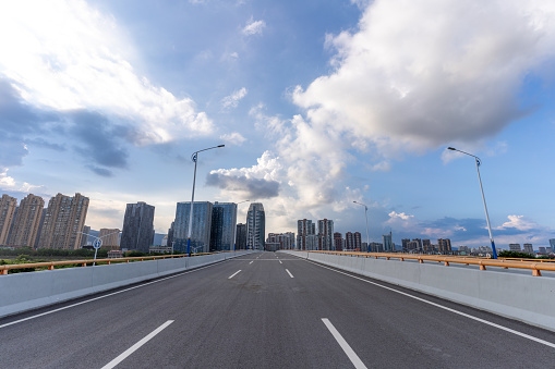 Empty highways and urban skyline under blue sky and white clouds