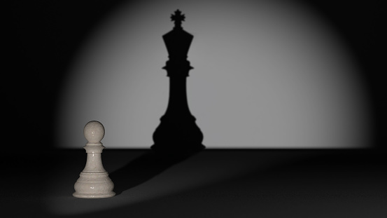A chess pawn that is illuminated and has the shadow of a chess king behind it, a success concept for young employees to create a shadow board in their career path