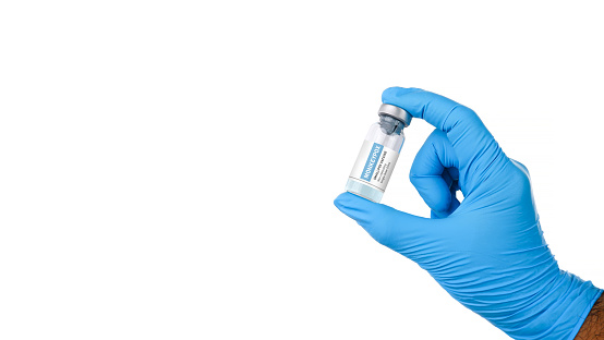 Monkeypox and smallpox virus vaccine bottle (MPXV) in a medical personnel hand with horizontal copy space on white background