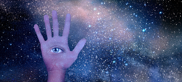 Conceptual close up open eye in palm of hand and Universe