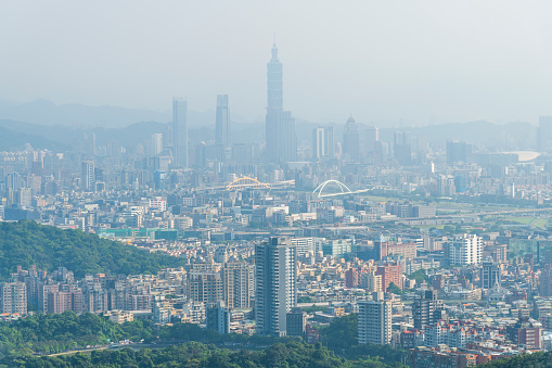 Overlooking view of the modern urban landscape of the Taipei area in Taiwan. It's a basin terrain surrounded by mountains.