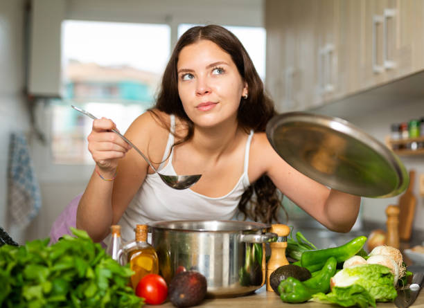 istock Young woman preparing soup in saucepan in kitchen 1413012960