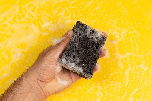 Hand with foam washing sponge .
