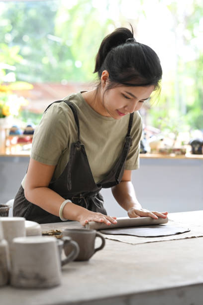 istock Female potter rolling pin for clay mass, making handicrafts at her studio. Creative hobby, ceramic works concept. 1413021989