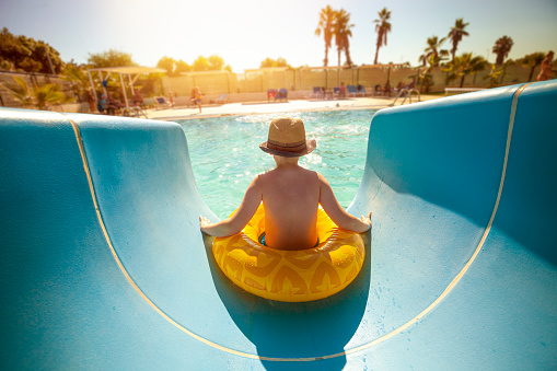 Boy on vacation playing in the waterslide in the inflatable ring