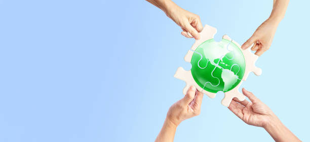istock Hands holding white jigsaw with green globe glass earth on light pastel background 1413025677