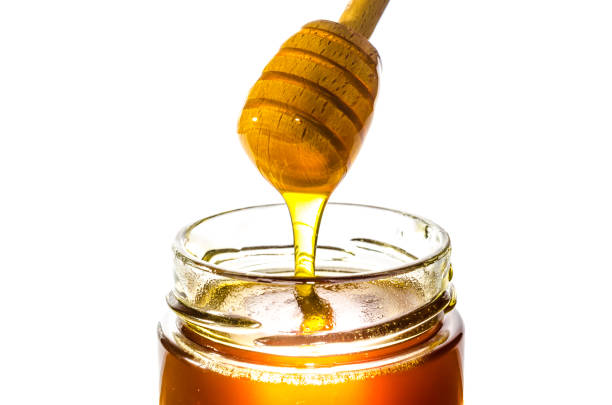 Honey on dipper from a jar stock photo