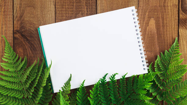 istock Notepad on a wooden table with fern leaves. 1413028589