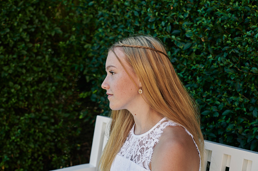 Fourteen year old girl in her official white confirmation dress standing outdoors near a church. Protestant confirmation