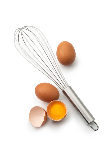 High angle view of Two eggs and one broken and whisk  isolated on a white background.