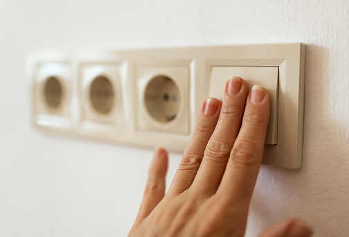 Fingers turn on or off light switch. Saving energy, electricity, power, energy crisis concept.