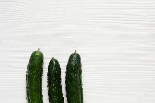 Cucumbers on white wood background. There is extra copy space for text.