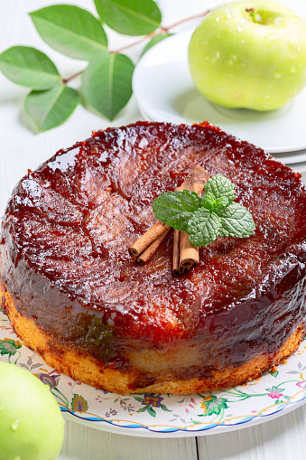Traditional apple tarte tatin with cinnamon is served with cinnamon sticks and fresh mint. Concept of homemade French pastries.