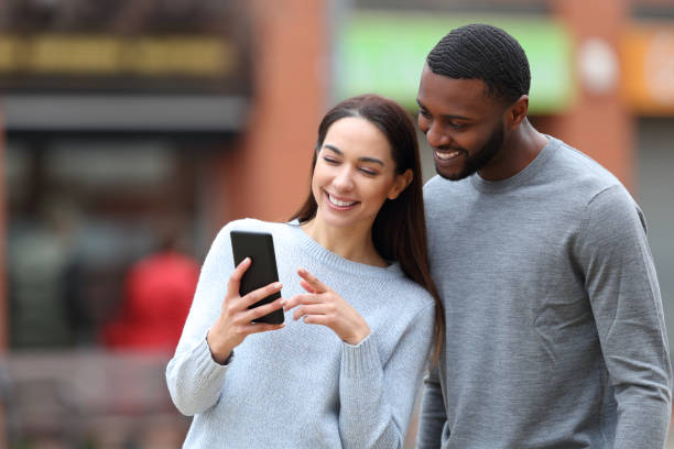 istock Happy interracial couple checking cell phone 1413036947