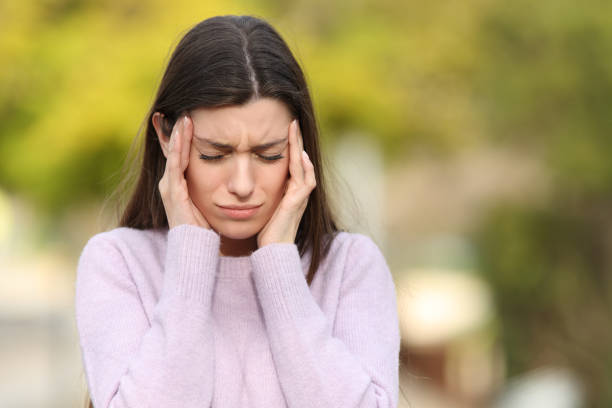 Teen stressed suffering migraine in a park stock photo