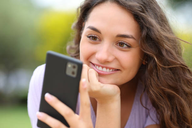 istock Happy woman reading message on phone in a park 1413037172