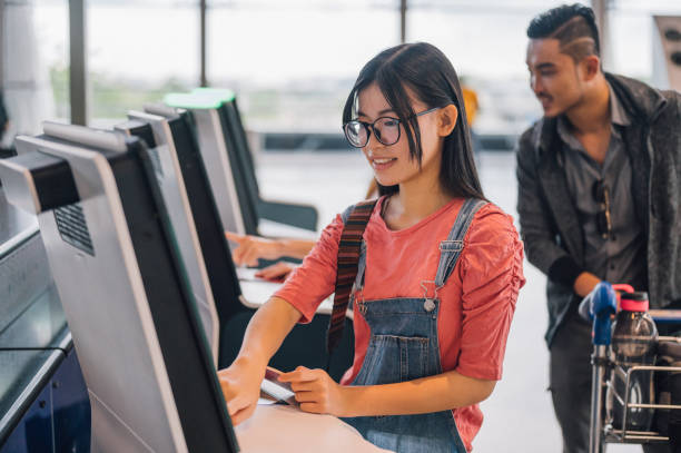 young asian female traveler using the check-in machine at the airport getting the boarding pass. individuals business travelling concept. - airport airport check in counter ticket ticket machine imagens e fotografias de stock