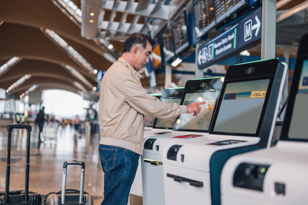 senior asian man using automated check-in machine in airport - self service stockfoto's en -beelden