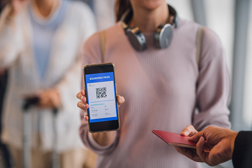 Image of passenger showing her electronic boarding pass on smartphone screen to airline attendant