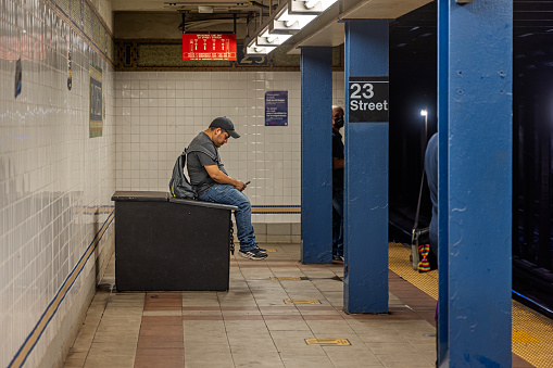 Manhattan, New York, NY, USA - June 26, 2022: Man sitting on a box at 23rd Street subway station